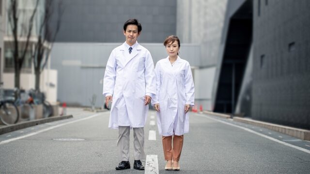 道の真ん中に立つ二人の薬剤師の男女
